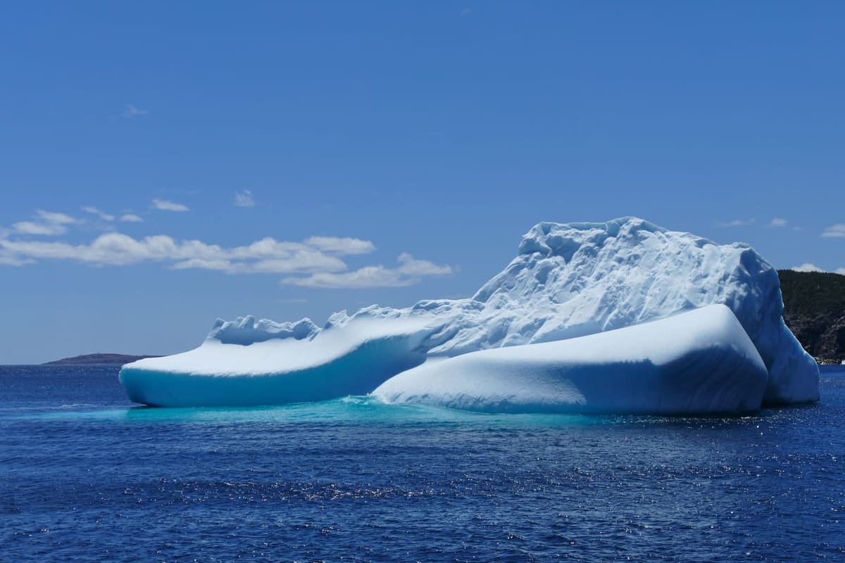 A weathered iceberg grounded off the Newfoundland coast under a grey sky