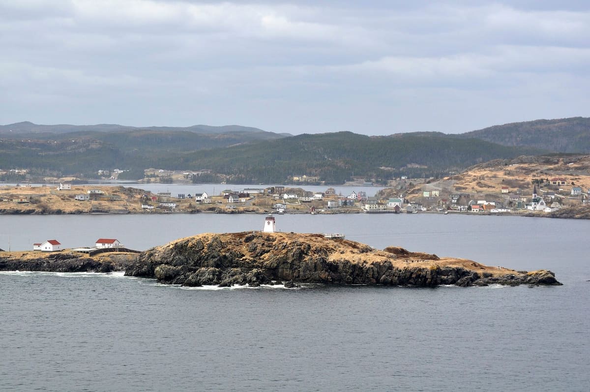 Painted wooden houses and a church around the sheltered harbour at Trinity, Newfoundland